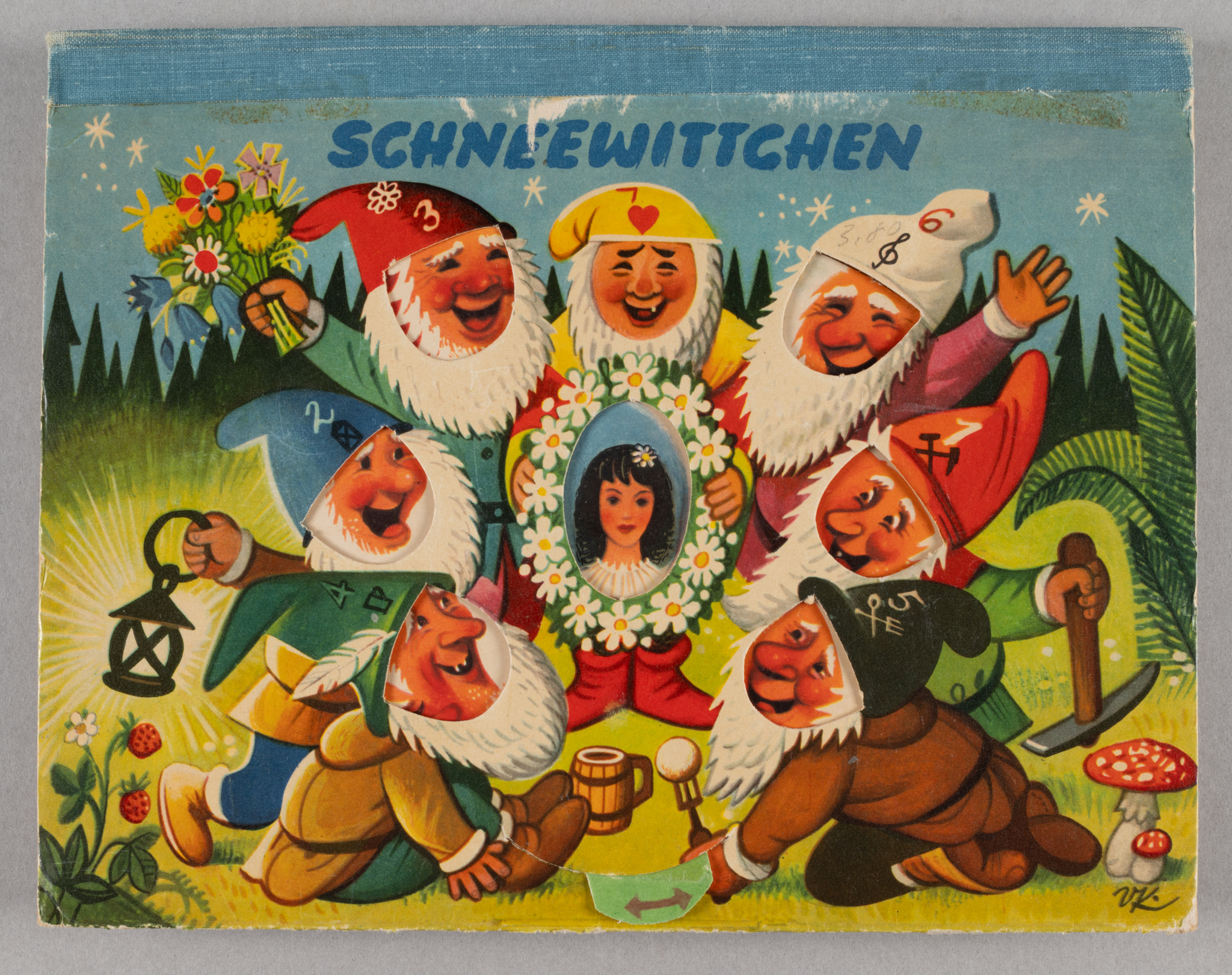 restored cover of a pop up book with image of seven dwarves in peaked, numbered caps circling a wreath of flowers in which an image of a girl appears when the pop up mechanism is manipulated