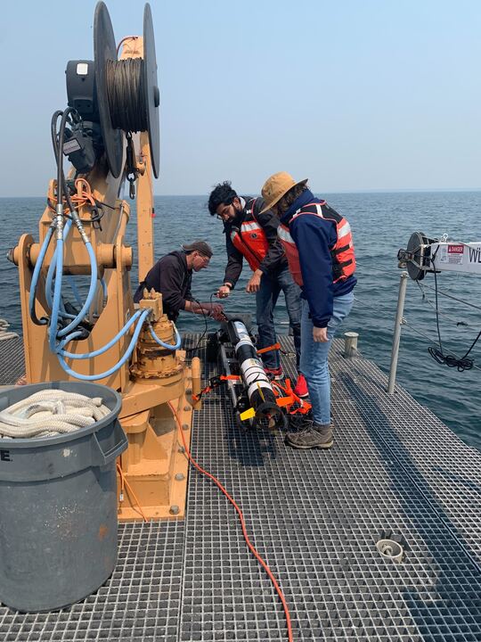 Three researchers preparing their sonar instrument on Lake Huron