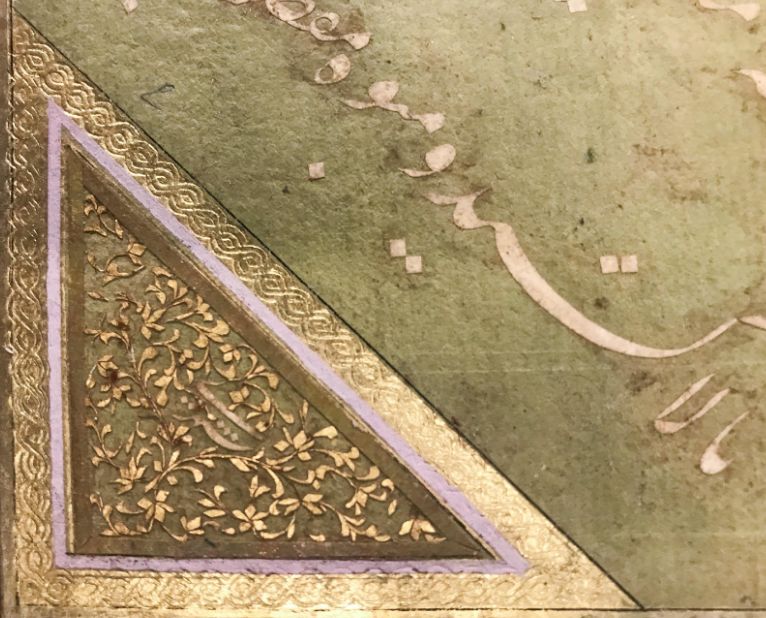 close view of line of cut-out calligraphy in persian with artist signature surrounded by a vegetal design in a cornerpiece
