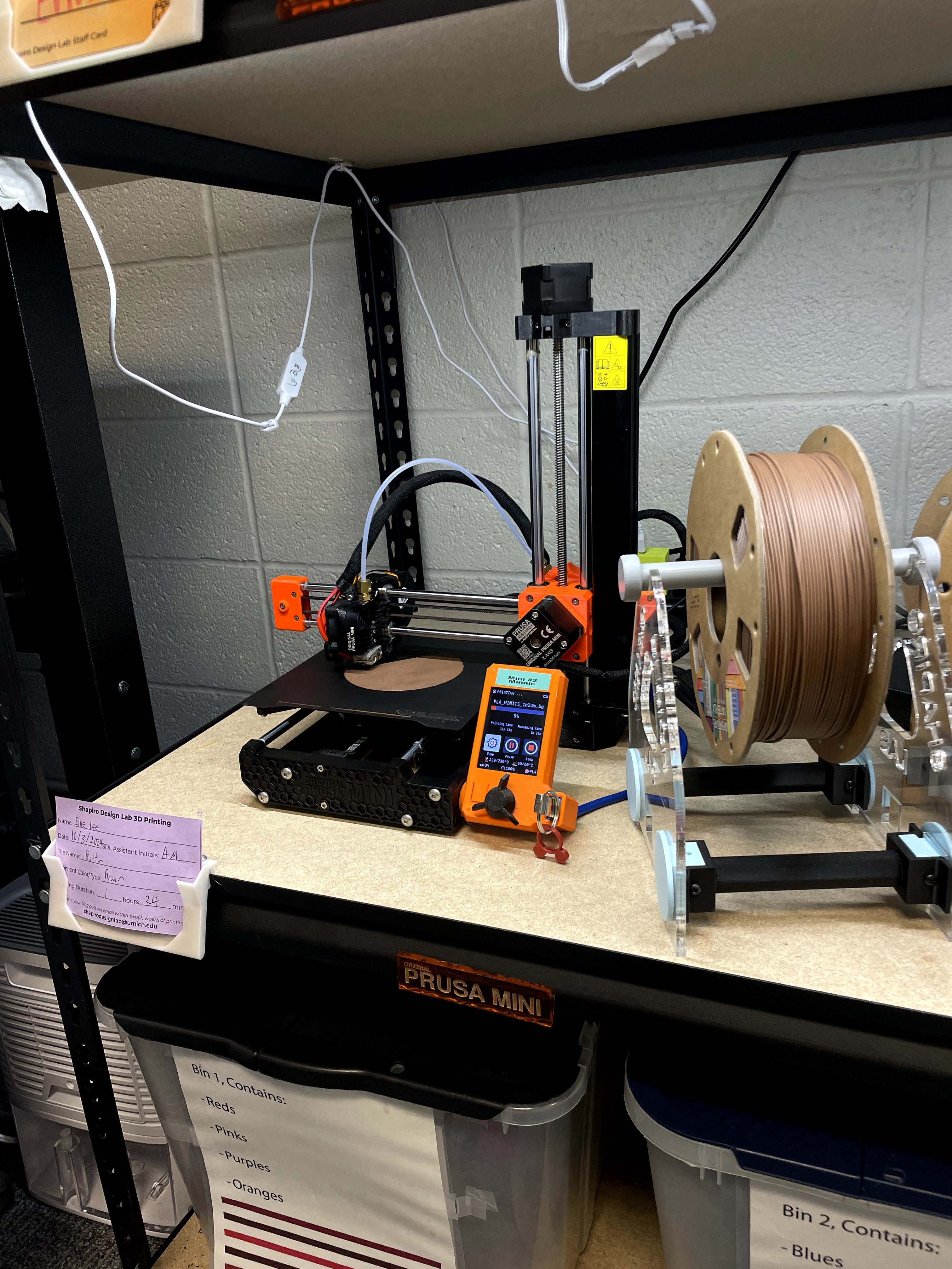 A 3D printer in action printing with brown filament the first layer of the 3D print is not yet complete. 