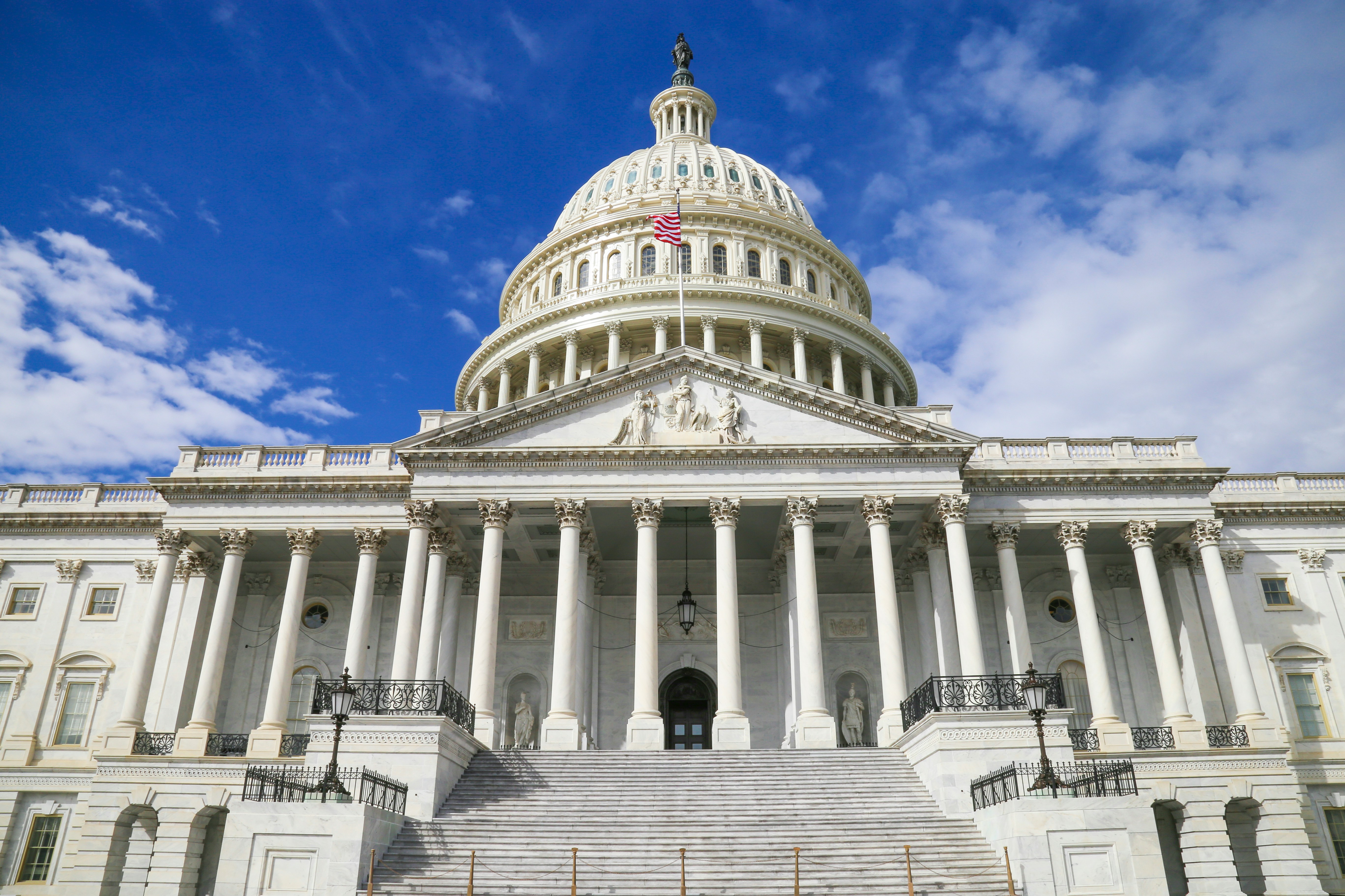 The U.S.A. Capitol Building against a bright, blue, sky littered with clouds