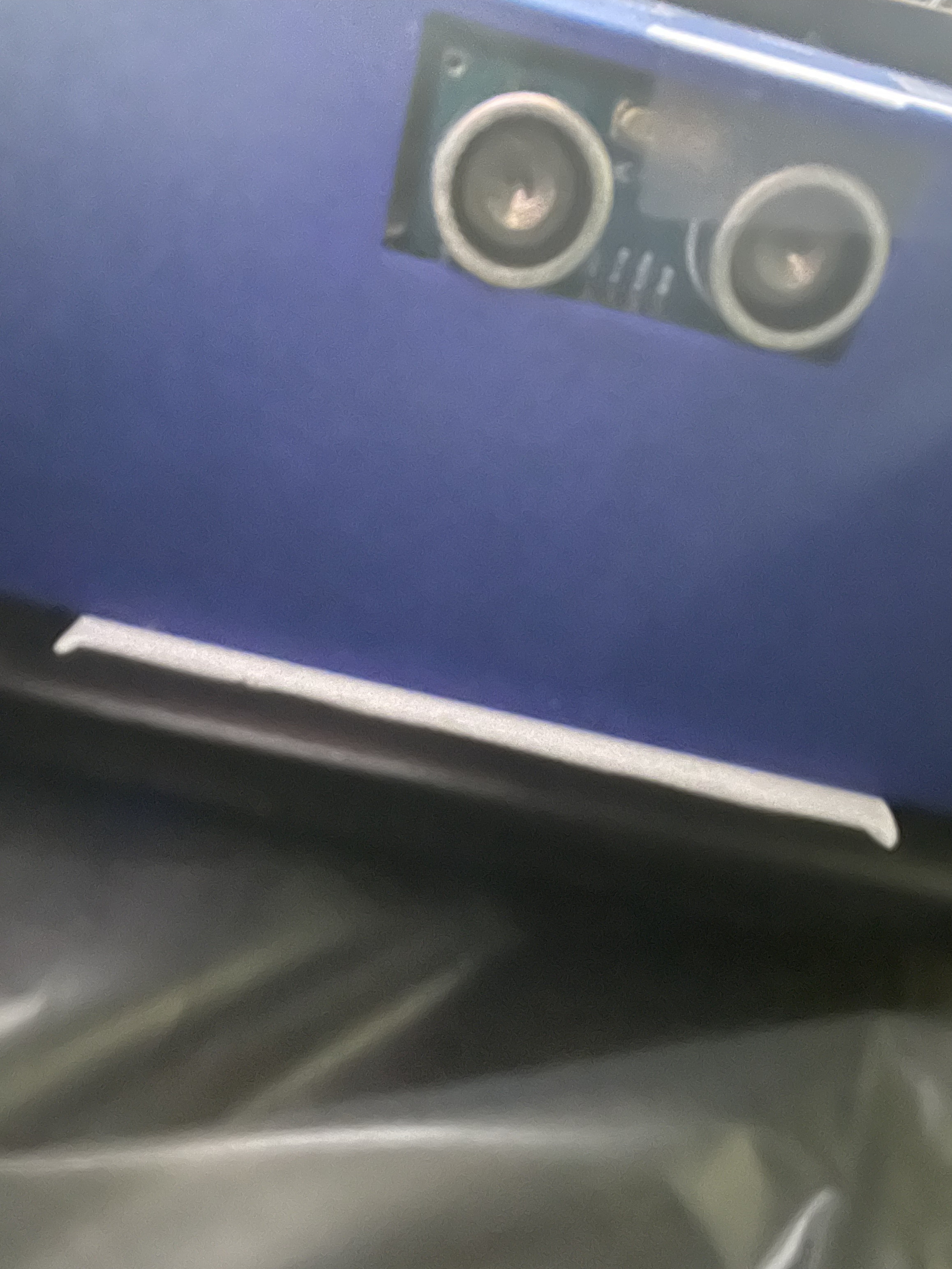 a 3d printed blue case - one side of the case is shown with a small rectuangular hole at the top, where two sensors on the inner circuitboard are showing. 