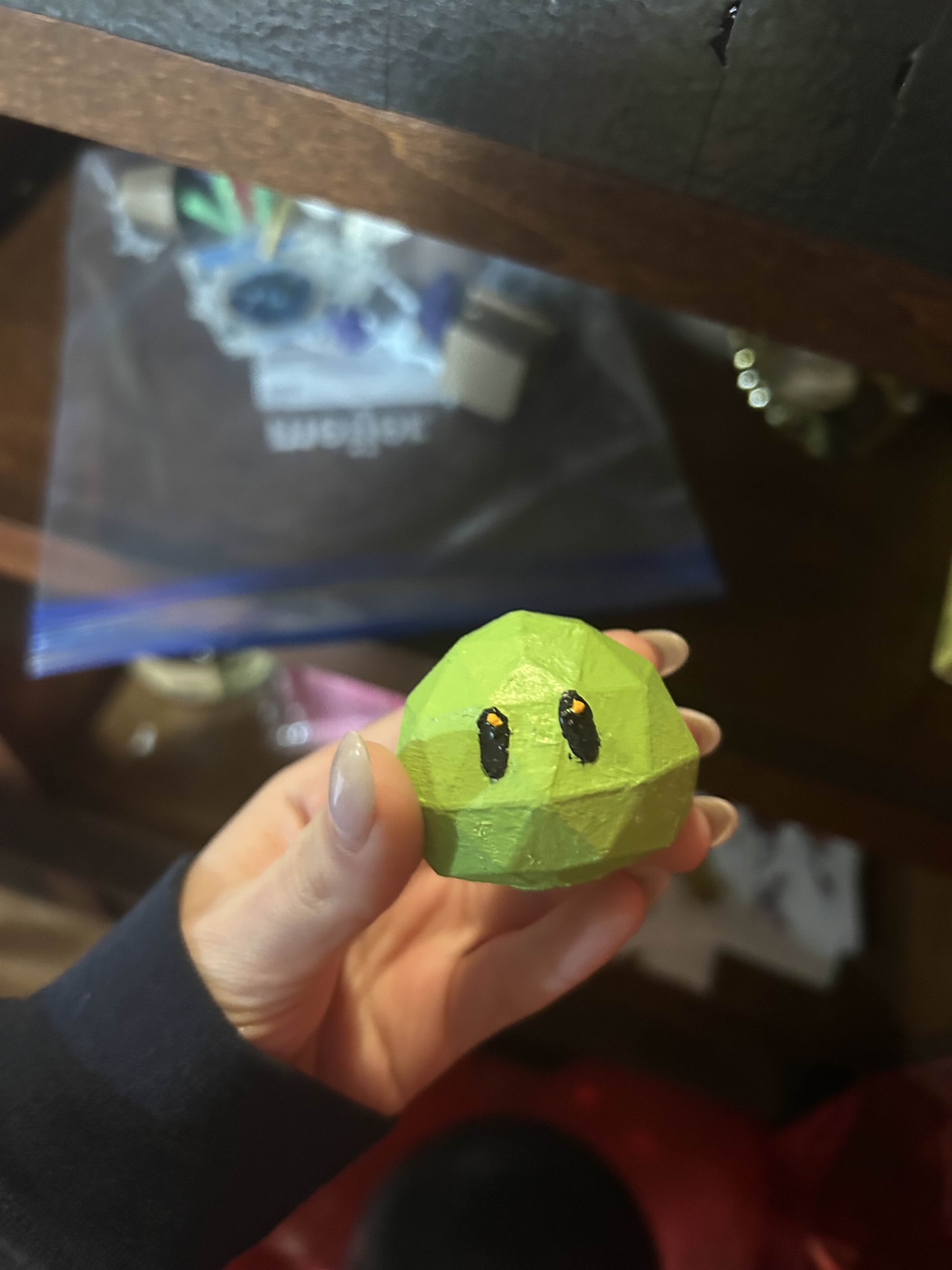 A small 3D printed slime - it is round, and lime green with black eyes.