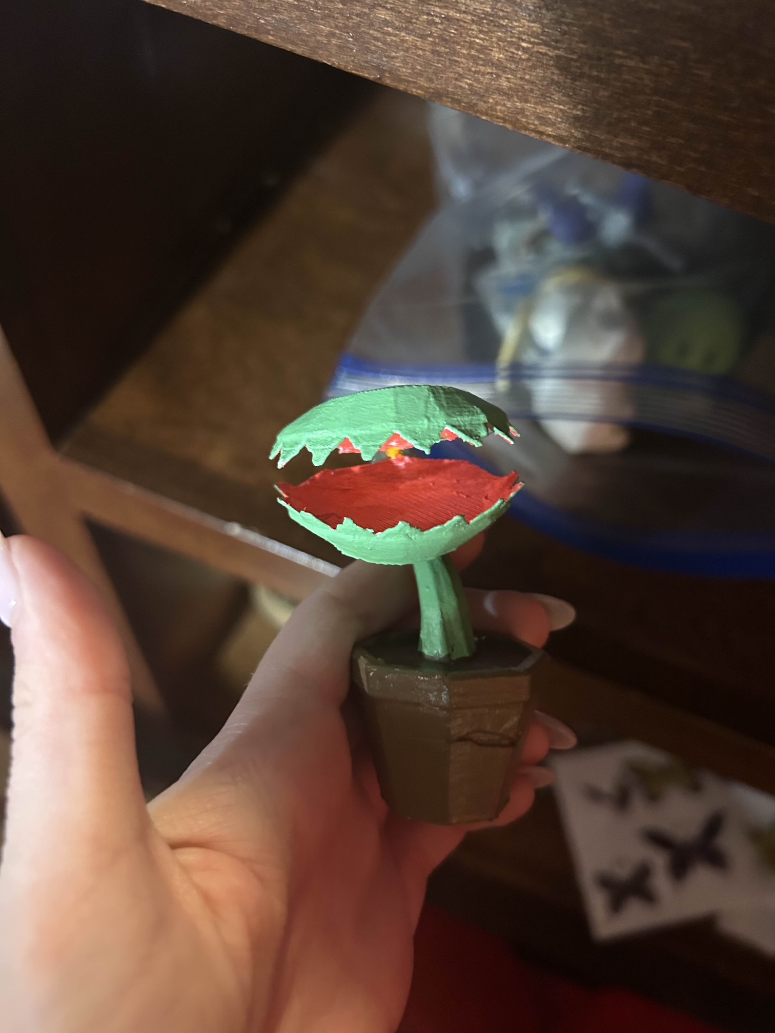 A small 3D printed figure of a venus fly trap. The Venus Fly Trap is green, and the inside of the mouth is red; it is in a brown pot.