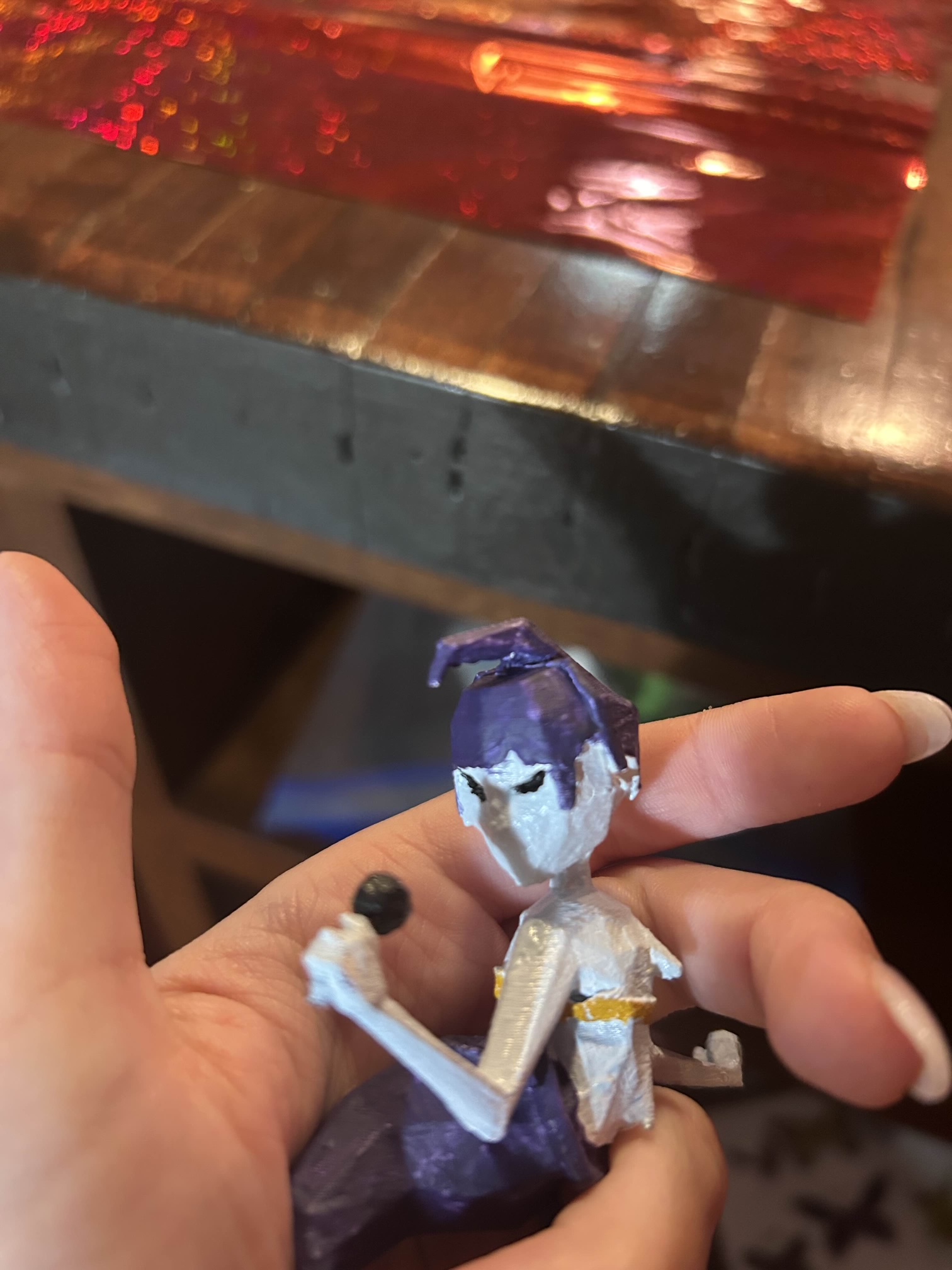 A small 3D printed figurine of a siren. It is a blue person with a blue mermaid tail and blue hair, with a black microphone they are "singing" into.