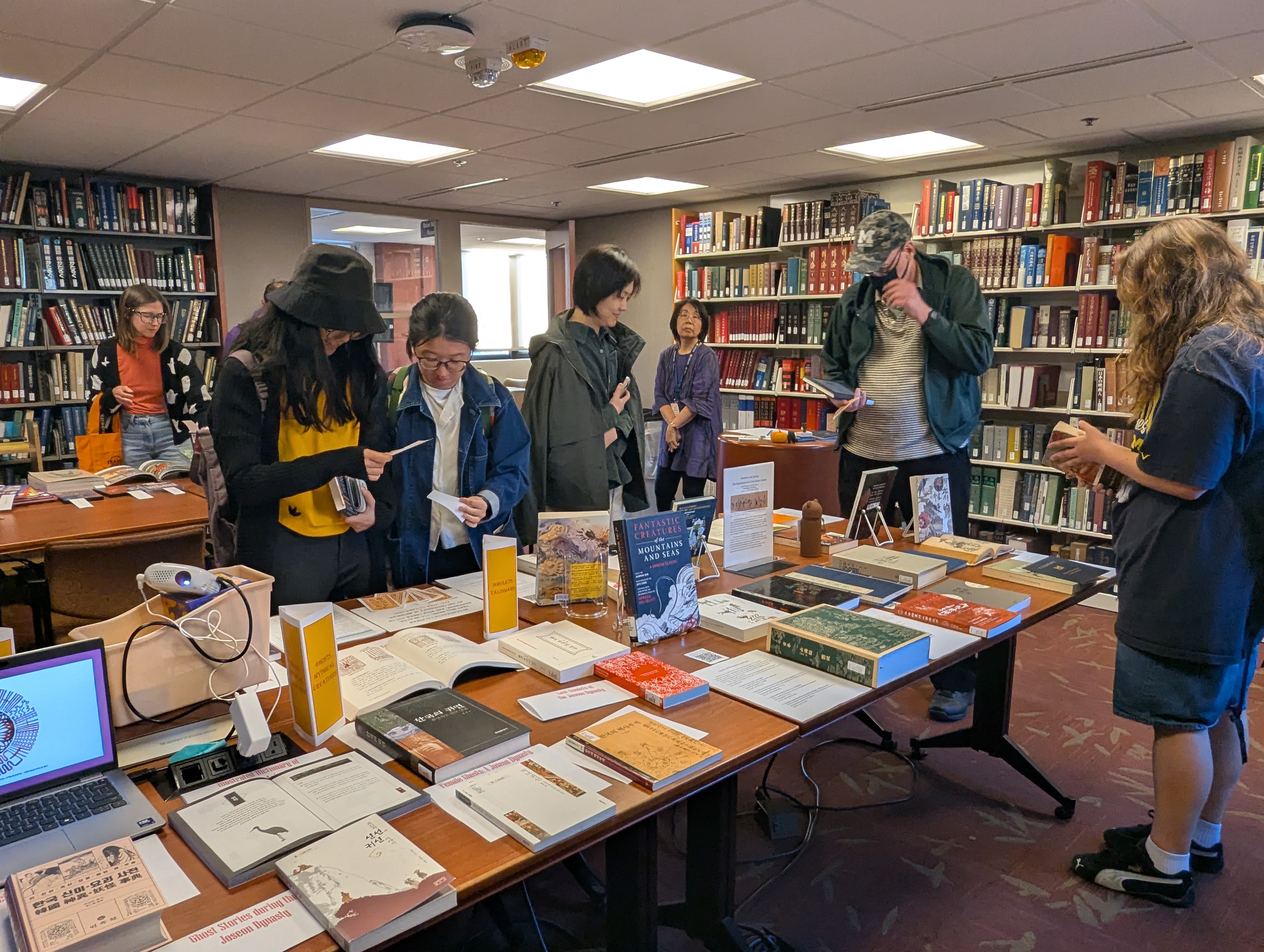 A picture of visitors at the Asia Library Third Thursday event, browsing items on display with interest