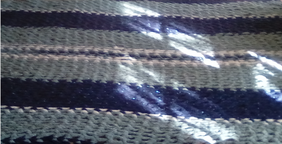 A close-up of a few rows of the completed blanket. From the bottom of the picture, the blanket alternates in gray and dark-blue stripes of about 6 rows each, with a small stripe of white-blue-white (1 yarn row each) in the middle of the picture.