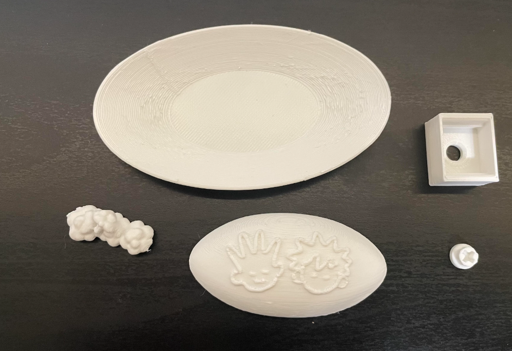 unfinished oval, square, and odd-shaped fidget clicker pieces in white on a grey-black background