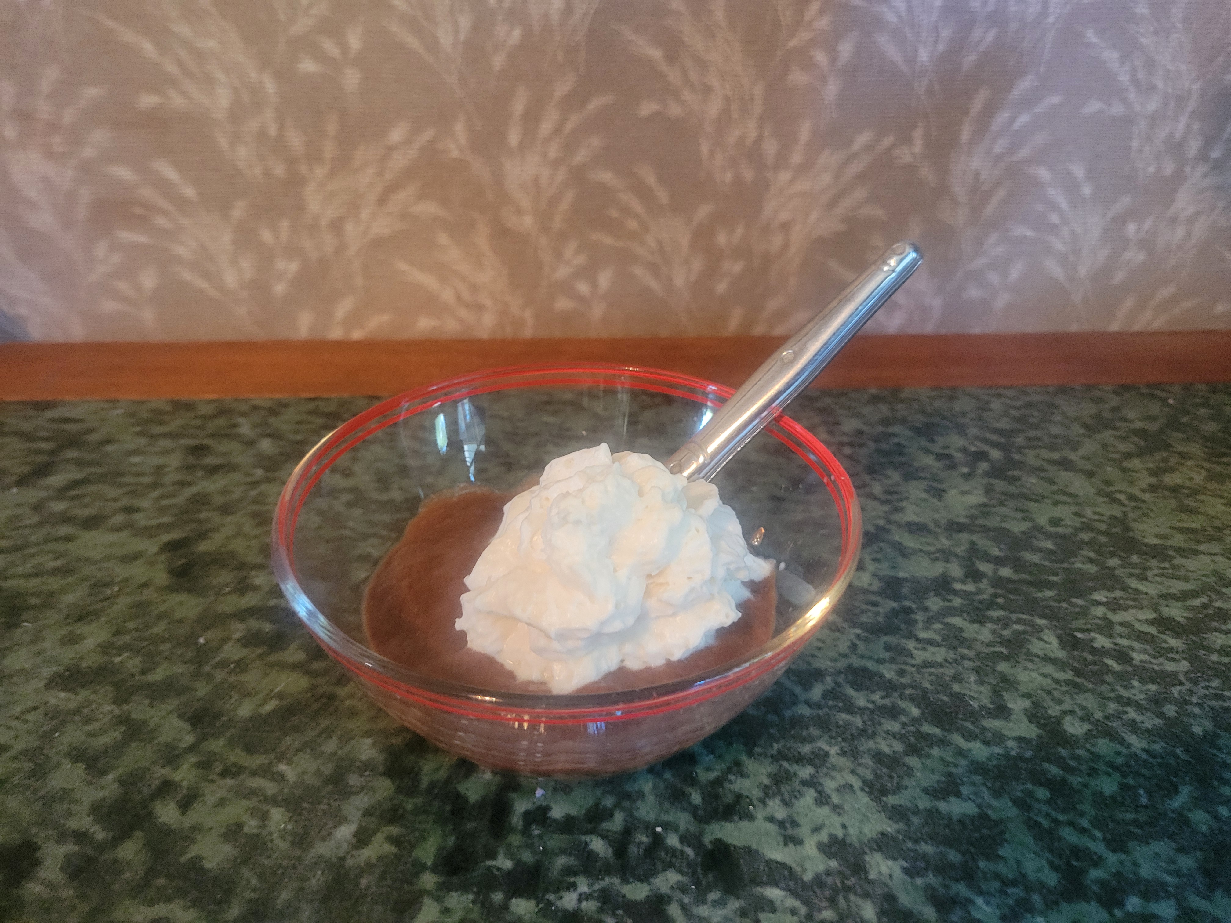 Glass bowl with chocolate pudding topped by whipped cream