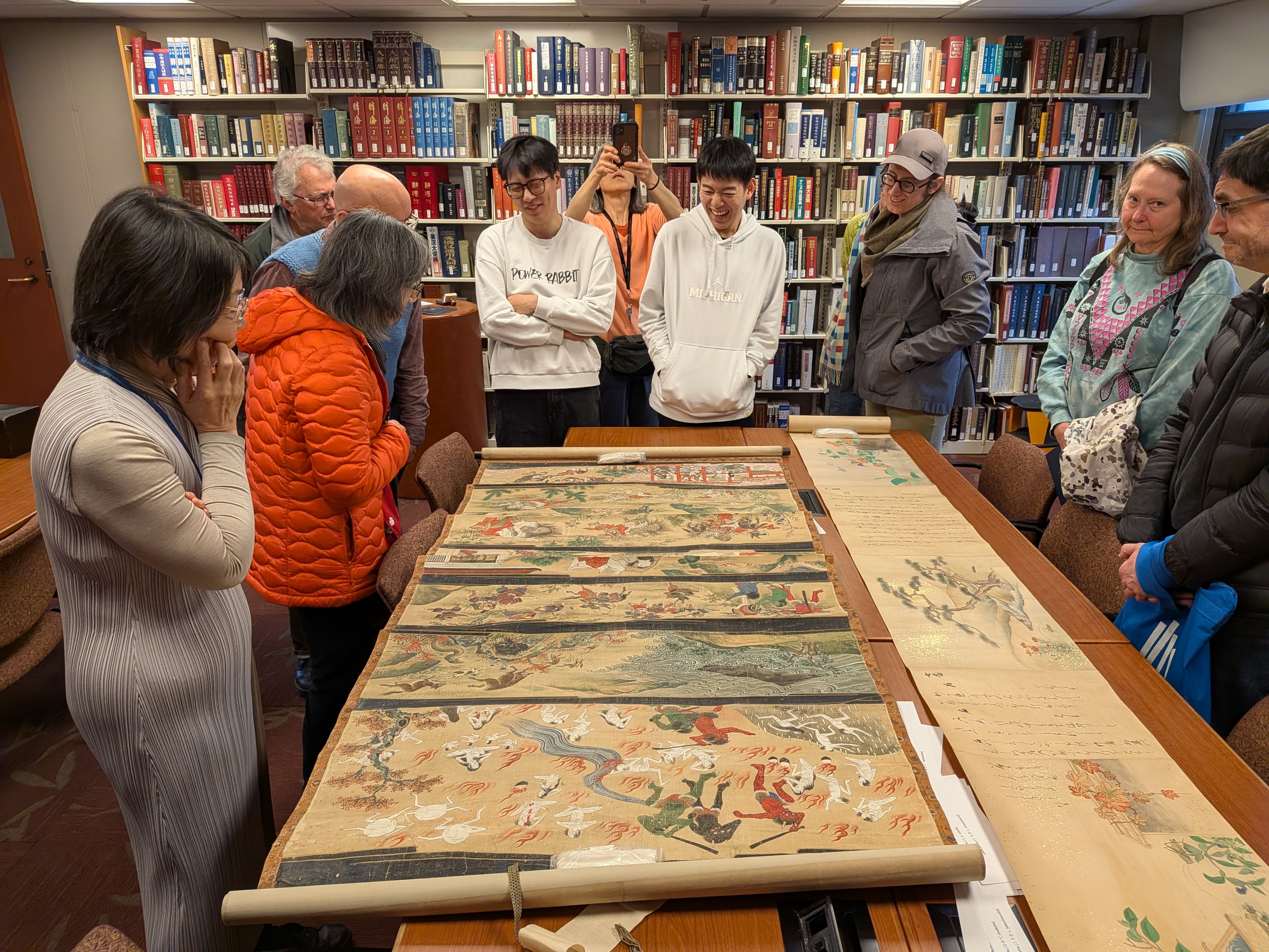 A picture of visitors at the Asia Library Third Thursday event, browsing two Japanese rare scrolls