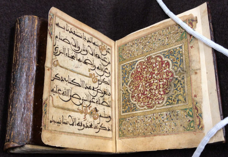 open book with arabic script in gold and colors