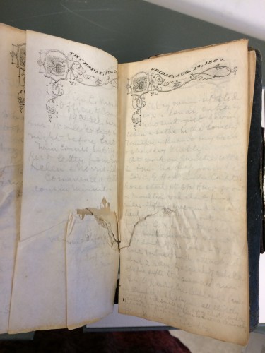 Photo of diary open, showing hole in pages