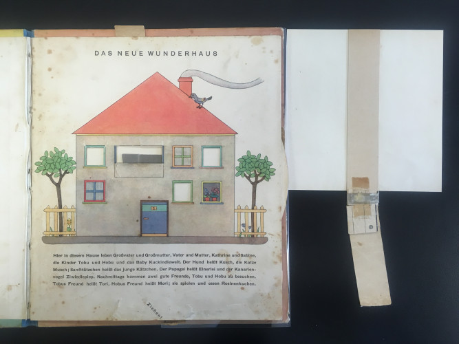 view of an open book with colored drawing of a house with free pull tab beside it