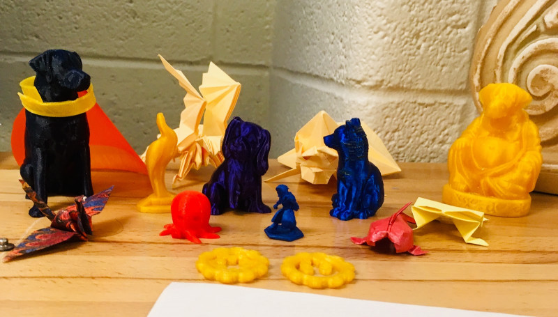 Selection of nine 3D printed figures and several origami items displayed in the Design Lab