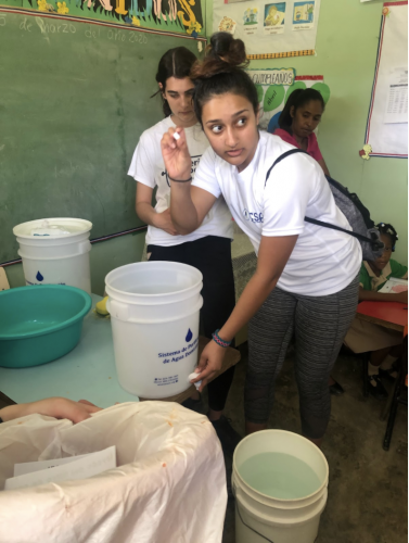 Student participant explains how to clean and use the water filter to the teachers
