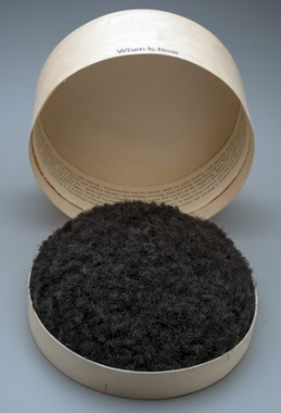 round wooden box of furry black stuff