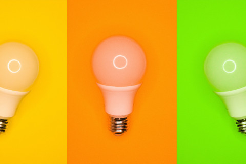 Vertical striped background in yellow, orange, and green with a lightbulb in front of each.