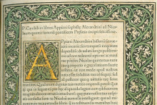 printed page of latin text with large initial A and border of vines and leaves in black with green and gold accents