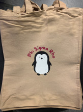 A beige Tote bag with a cute Penguin with Phi Sigma Rho on the top