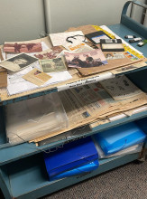 Folders, newspapers, and pictures from the Marcelo Mirisola Papers collection on a cart.