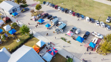 Aerial view busy parking lot near row of colorful tents with people shopping at farmer market near Dallas, Texas, USA