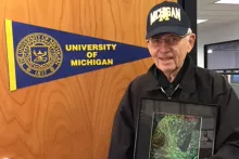 Arnold Heyman standing next to a University of Michigan banner.