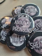 Pin-back buttons with the top button saying "Ask me about my pronouns."