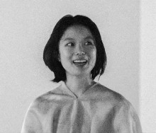 A black and white image of an Asian woman smiling and looking to her left