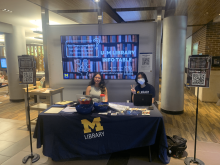Library Student Ambassadors Alyssa Wakefield and Grace Tai sitting at an information table.