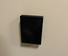 A black 3D Printed cover fully covering an AC control panel on a beige wall.
