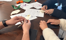 The hands of students folding Halloween-themed origami.