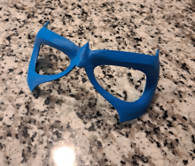 A blue 3d printed eye mask sitting on a granite counter.
