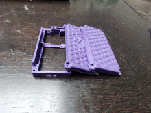 A purple 3D printed rectangular case in three parts - one outline with a support cross-beam (for the width of the device) and two panels for the front and back of the device.