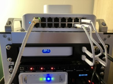 The back of a router with a black 3D printed mount in the middle. There are lots of wires and ports connected into the router.