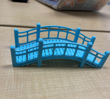 A 3D printed blue arched garden bridge with railings.