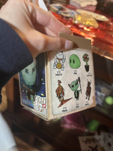 The outside of an illustrated cardboard box. On the side of the box is six small drawings of possible "collectible" figures - a lucky cat, a slime, a venus fly trap, a phoenix, a goblin, and a minotaur.