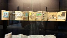 A 9-page plywood booklet standing up and spread out in a glass display case. The pictures in the pages are detailed using laser engraving, and then painted over using bright, heavy coats of paint. The story involved many small, cartoon-like animals in a restaurant.