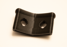 A black 3D printed curved piece meant for the end of a trowel. The piece is short and longer, with a folding seam down the middle, going with the curve. On either side of the angled seam, there is a circular hole that goes through the print (2 holes in total).