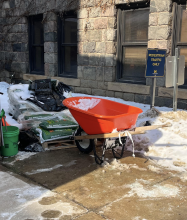 Sunlight shining on red wheelbarrow parked in snow (which will be used for Winter Sowing Event)