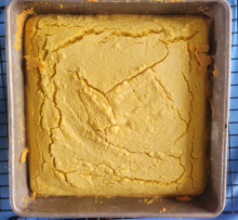 Square pan of yellow cornbread, showing cracks typical of quick breads