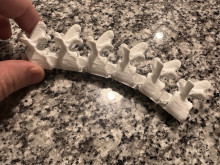A white 3D printed spine model on a granite countertop.