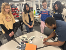Erica Ervin showing students how to apply a design to a pencil case.
