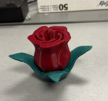 A 3D printed rose. The petals of the rose are red, and the leaves underneath are green - the petals sit on top of the leaves.