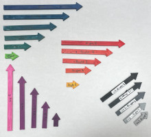 A series of 3D printed multi-colored arrows on a white background. There are long blue, pink, and red arrows, medium length black, gray, and purple arrows, and short light orange, lime green, and purple arrows.