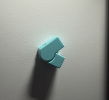 A Light blue 3D printed hinge joint on a white surface. The hinge is "closed" in a v-shape pointing to the left of the image.