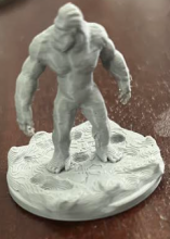 Grey 3D printed dungeons and dragons character on a brown background.