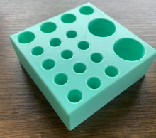 Mint green colored test tube support box on a dark wood grain background