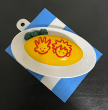 A fidget clicker featuring two faces outlined in red on a yellow background 