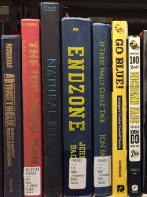 Picture of spines of books about Michigan football history in the Hatcher Graduate library.