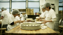 Photograph of a scene from the film Soul of a Banquet, depicting a kitchen with cooks making dumplings